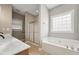 Elegant bathroom featuring a soaking tub, separate shower, and neutral tile flooring at 105 Bagley Ln, Dunn, NC 28334