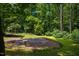 A stone patio is surrounded by mature trees and landscaping at 106 Redbud, Pittsboro, NC 27312