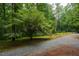 Long gravel driveway leads to a charming wooded lot with a beautiful blooming dogwood tree at 106 Redbud, Pittsboro, NC 27312