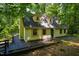 Inviting two-story home with a charming yellow exterior and spacious deck, nestled among lush green trees at 106 Redbud, Pittsboro, NC 27312