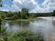 Scenic river view with lush green vegetation and a waterfall in the distance at 106 Redbud, Pittsboro, NC 27312