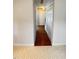 Hallway with hardwood floors transitioning to tiled flooring, leading to a white door and closet space at 109 Elmview Dr, Cary, NC 27519