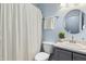 Blue bathroom featuring a shower with curtain and a round mirror at 109 Faldo Cv, Raleigh, NC 27603