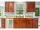 Kitchen area featuring a stainless steel dishwasher and sink under a window with wood cabinets at 109 Faldo Cv, Raleigh, NC 27603