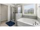 Bright bathroom featuring a glass shower, soaking tub, tiled walls, and natural light from the window at 1165 Sun Spgs Rd, Wake Forest, NC 27587