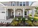 A detailed shot of the inviting covered front porch with brick accents and a manicured garden at 1165 Sun Spgs Rd, Wake Forest, NC 27587
