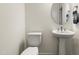 A modern powder room with a pedestal sink, round mirror, and neutral color scheme at 1165 Sun Spgs Rd, Wake Forest, NC 27587