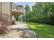Stone patio and manicured lawn with a deck and mature trees at this backyard at 117 Synandra Ln, Holly Springs, NC 27540