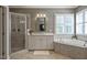 Bright bathroom features a glass shower, soaking tub, and white vanity with marble countertops at 117 Synandra Ln, Holly Springs, NC 27540