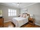 This cozy bedroom has wood floors, ceiling fan, and natural light from the window at 117 Synandra Ln, Holly Springs, NC 27540