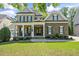 Charming brick home featuring a covered front porch, manicured lawn, and mature landscaping at 117 Synandra Ln, Holly Springs, NC 27540