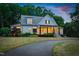 Charming home with a curved driveway, manicured landscaping, and warm exterior lighting at dusk at 125 Lord Ashley Rd, Raleigh, NC 27610