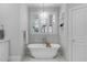 Bright bathroom featuring a soaking tub, marble floors, a pendant light, and a shuttered window at 1305 Queensferry Rd, Cary, NC 27511
