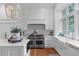 Bright white kitchen with a large center island, Wolf range, and farmhouse sink at 1305 Queensferry Rd, Cary, NC 27511