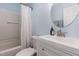 Bright bathroom featuring a white vanity, round mirror, and a shower/tub combo with light blue painted walls at 139 Hollyhock Ct, Durham, NC 27713