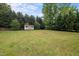 Spacious backyard featuring a shed, surrounded by mature trees and lush greenery, creating a private outdoor space at 1416 Chestnut St, Roxboro, NC 27573