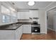 Well-lit kitchen features white cabinets, stainless steel appliances, and wood-look flooring at 1416 Chestnut St, Roxboro, NC 27573