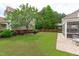Landscaped backyard featuring a lush lawn, mature trees, and a brick patio at 1514 Hinchliff Ct, Fuquay Varina, NC 27526