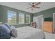Well-lit bedroom with carpet, green walls, ceiling fan, dresser, and a view of the backyard at 1514 Hinchliff Ct, Fuquay Varina, NC 27526