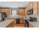 Modern kitchen featuring oak cabinets, a black appliance package, and a tile backsplash at 1514 Hinchliff Ct, Fuquay Varina, NC 27526