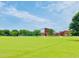 Expansive green field with playground and Ballentine Elementary School in the background at 1514 Hinchliff Ct, Fuquay Varina, NC 27526