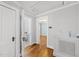This hallway features hardwood floors and fresh paint that leads to an airy room and the main bathroom at 1812 Hilton St, Raleigh, NC 27608