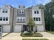 Modern townhome featuring brick, white, and gray facade, complemented by individual garages and well-manicured landscaping at 1900 Fishamble St # 17, Fuquay Varina, NC 27526