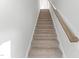 Carpeted staircase with wooden handrail and white walls leads to the upper level of the home at 1900 Fishamble St # 17, Fuquay Varina, NC 27526