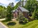 Beautiful exterior view of a brick home framed by mature trees and a lush green lawn on a sunny day at 203 Worsham Dr., Chapel Hill, NC 27516