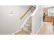 Carpeted staircase with white risers, a wood handrail, and a view of the kitchen at 203 Worsham Dr., Chapel Hill, NC 27516