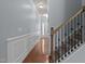 Inviting hallway with hardwood floors, wainscoting, and staircase with wrought iron railing at 2082 Weston Green Loop Loop, Cary, NC 27513