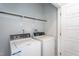 Bright laundry room featuring white washer and dryer units, along with overhead shelving at 228 Shingle Oak Rd, Wake Forest, NC 27587
