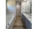 Bathroom with double sink, vanity, granite countertop, soaking tub, and wood look flooring at 240 Eason Creek Way, Clayton, NC 27527