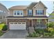 Charming two-story home featuring a stone facade, covered porch, attached two-car garage, and manicured landscaping at 241 Fishburn Dr, Apex, NC 27523