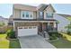 Beautiful home boasting stone accents, a front porch with seating, well-maintained lawn, and a two-car garage at 241 Fishburn Dr, Apex, NC 27523