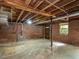 Unfinished basement with exposed brick walls, wooden ceiling, concrete floors, and natural light at 2434 Morningside Dr, Burlington, NC 27217