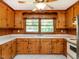 Charming kitchen featuring knotty pine cabinets, a ceiling fan, and a garden window overlooking the backyard at 2434 Morningside Dr, Burlington, NC 27217