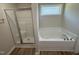 Bright bathroom showcases a shower, a bathtub, a window, and neutral colored walls at 245 Eason Creek Way, Clayton, NC 27527
