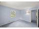 Comfortable bedroom featuring natural light from a window, soft blue walls, and a cozy carpeted floor at 3025 Wycliff Rd, Raleigh, NC 27607
