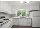 Updated kitchen with white appliances, countertops, and a window overlooking the backyard at 3025 Wycliff Rd, Raleigh, NC 27607