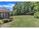 Manicured backyard with green lawn, lush trees, and access to screened-in porch on home at 3108 Lawson Walk Way, Rolesville, NC 27571