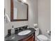 Powder room features a dark vanity with stone countertop, framed mirror, and white toilet alongside towel and flower decor at 3108 Lawson Walk Way, Rolesville, NC 27571