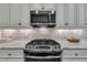Modern kitchen features stainless steel stove with microwave above, granite counters, and white cabinets with stone backsplash at 3108 Lawson Walk Way, Rolesville, NC 27571