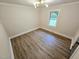 Open bedroom with hardwood floors, modern light fixture, and a view of greenery at 3669 W Greensboro Chapel Hill Rd, Liberty, NC 27298