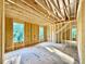 A bedroom under construction, highlighting wood framing, multiple windows, and a view of surrounding trees at 3828 Coach Lantern Ave, Wake Forest, NC 27587