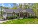 Charming home exterior showcases manicured lawn, stone accents, covered porch, and lush landscaping at 4036 Mackenzie Dr, Haw River, NC 27258