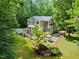 Aerial shot of the home features an outdoor dining space, well-manicured lawn, and lush surrounding landscape at 406 Johns Woods Rd, Chapel Hill, NC 27516