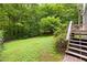Landscaped backyard featuring a lush lawn, bordered by mature trees and steps to the upper deck at 406 Johns Woods Rd, Chapel Hill, NC 27516