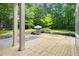 Inviting backyard patio with wooden deck and stone sitting area surrounded by lush greenery at 406 Johns Woods Rd, Chapel Hill, NC 27516