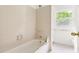 Bathroom featuring a shower-tub combo with white tiles and a window offering natural light at 406 Johns Woods Rd, Chapel Hill, NC 27516